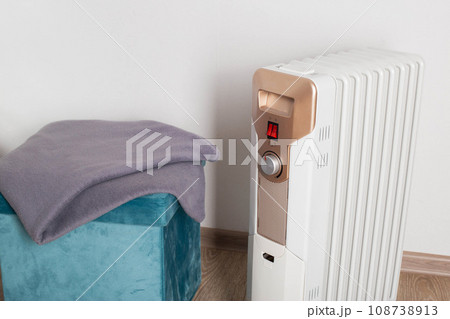 Electric heater on a white background next to a warm blanket. The concept of fire safety during the cold period when using an electric heater. Copy space for text, industry Electric heater on a white background next to a warm blanket. The concept of fire safety during the cold period when using an electric heater. Copy space for text, industry 108738913