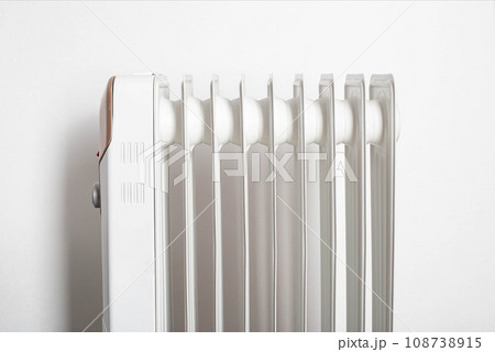Modern electric oil heater on a white background. Heating the room. Heating season in apartments, close-up 108738915