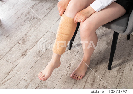 Orthopedic medical kneecap on the leg of a girl. Fixation and support of the knee joint after injury. Orthopedic medical kneecap on the leg of a girl. Fixation and support of the knee joint after injury. 108738923