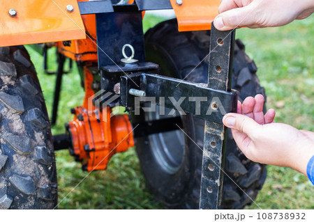Adjustment of the coupling and attachments in a multifunctional motor cultivator for cottages. Close-up Adjustment of the coupling and attachments in a multifunctional motor cultivator for cottages. Close-up 108738932
