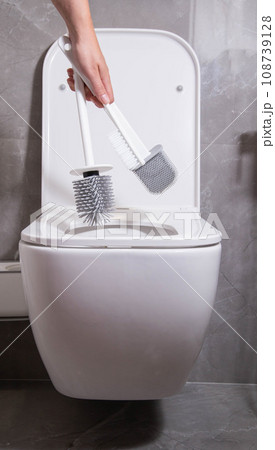 The girl in her hand holds three silicone brushes for the toilet. The concept of care and hygiene for the toilet bowl and seat. Prevention of pollution and cleaning of bacteria, close-up 108739128