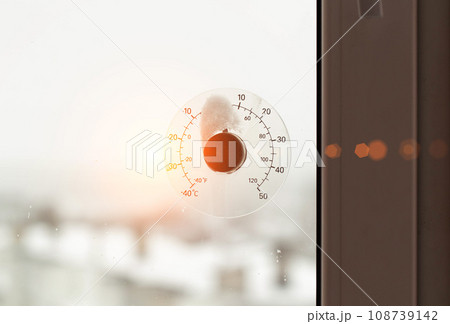 Rays of the sun against the background of a street thermometer with a snow cap. The concept of frosty weather and cooling in winter. Copy space for text, dependence 108739142