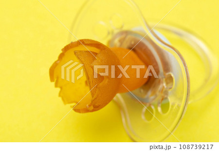 A chewed baby pacifier on a yellow background. Concept of teething in children, close-up. A chewed baby pacifier on a yellow background. Concept of teething in children, close-up. 108739217