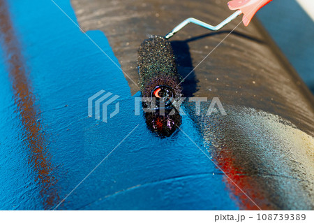Metal pipe is painted with paint roller with black paint or bitumen. Protection of metal pipes from Metal pipe is painted with paint roller with black paint or bitumen. Protection of metal pipes from 108739389