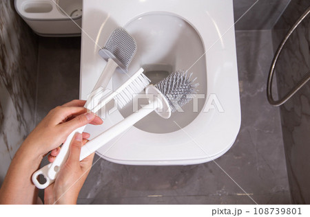 The girl in her hand holds three silicone brushes for the toilet. The concept of care and hygiene for the toilet bowl and seat. Prevention of pollution and cleaning of bacteria, close-up 108739801