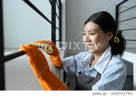 Hands in blue rubber gloves holding microfiber cleaning cloth make cleaning and disinfection for good hygiene of a stair railing Hands in blue rubber gloves holding microfiber cleaning cloth make cleaning and disinfection for good hygiene of a stair railing 108741793