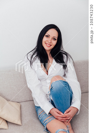 a woman in a free style sits in a room on a sofa 108743230