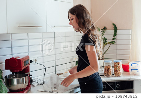 a woman in a white kitchen is going to make dough for cakes a woman in a white kitchen is going to make dough for cakes 108743815