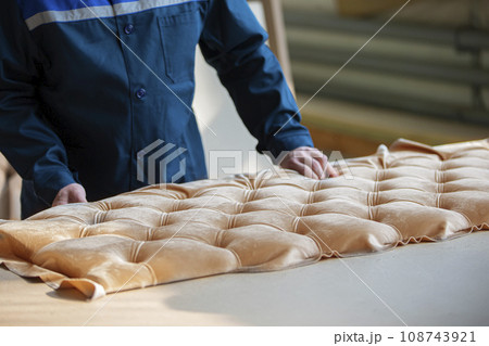 Worker's hands make furniture. Make a carriage screed on the sofa. 108743921