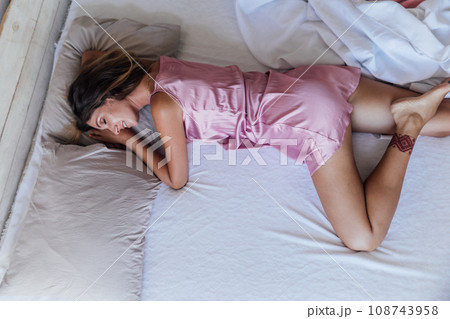 a woman in a pink nightgown sleeps in a bed in the bedroom a woman in a pink nightgown sleeps in a bed in the bedroom 108743958