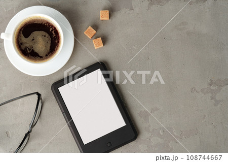 E-book reader with glasses on gray background close up E-book reader with glasses on gray background close up 108744667