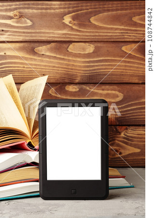 Digital tablet and stack of hardcover books against wooden background 108744842