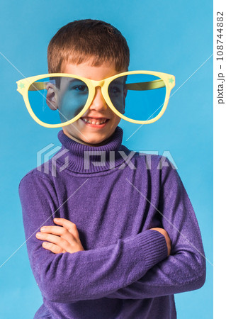 Cheerful little boy in big glasses express a surprised face isolated on blue background. Cheerful little boy in big glasses express a surprised face isolated on blue background. 108744882