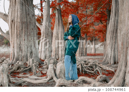 Woman walking among trees in park. Portrait of people in park in autumn. Woman walking among trees in park. Portrait of people in park in autumn. 108744961
