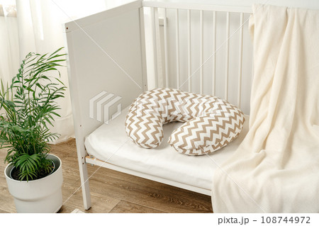 White wooden baby crib with pillow in nursery room White wooden baby crib with pillow in nursery room 108744972