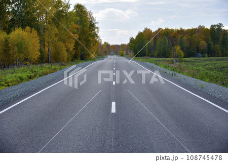 Beautiful autumn asphalt road through the forest. Highway is a road in a beautiful countryside. Beautiful autumn asphalt road through the forest. Highway is a road in a beautiful countryside. 108745478