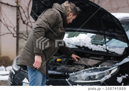 Man open hood of the car and trying to find out what is happened with car. Man scratches the back of is head. Winter outdoors 108745889