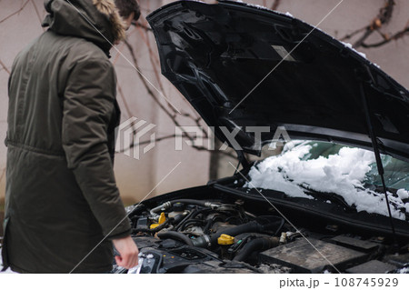 Close up of man open snowy hood of the car, winter outdoor 108745929