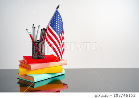 USA flag with pile of colorful books on black table USA flag with pile of colorful books on black table 108746153