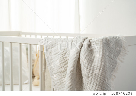 Muslin baby blanket hanging on child's bed in nursing room Muslin baby blanket hanging on child's bed in nursing room 108746203