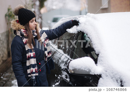 Woman clean car after night snowfall. Preparing to drive at work Woman clean car after night snowfall. Preparing to drive at work 108746866