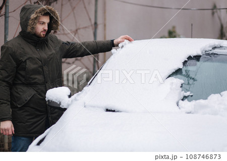 Man clean car from snow by hands after night snowfall 108746873