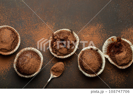 Chocolate browny muffins and cocoa in teaspoon top view on brown rustic stone background, sweet homemade dark chocolate cupcakes 108747706