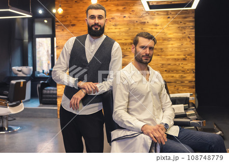 Man sitting on chair in barbershop with his master hairdresser. 108748779