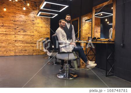Man sitting on chair in barbershop with his master hairdresser. 108748781