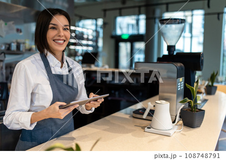 Girl in apron standing at the table in a coffee shop 108748791