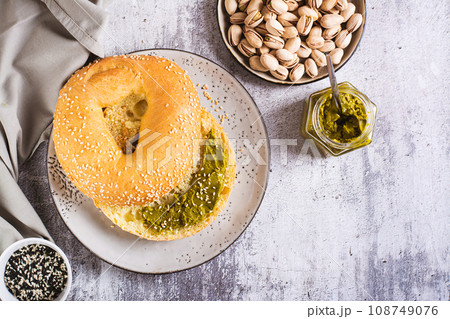 Bagel with pistachio cream butter for breakfast on a plate on the table top view Bagel with pistachio cream butter for breakfast on a plate on the table top view 108749076