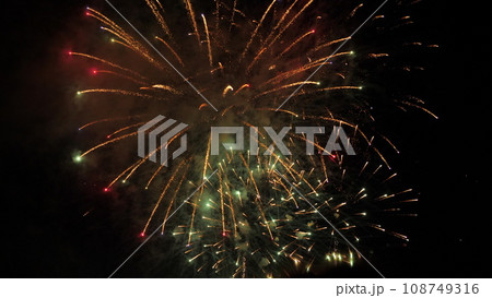 Fireworks sparkling flowers blasts with smoke cloud in black night sky. Fireworks performance of dazzling display for spectators at night. Fireworks holiday show with flashes blasts in sky 108749316