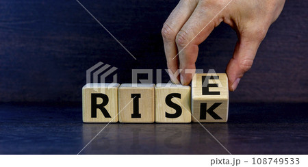 Risk vs rise symbol. Businessman turns a wooden cube and changes the word risk to rise. Beautiful grey background, copy space. Business, risk vs rise concept. Risk vs rise symbol. Businessman turns a wooden cube and changes the word risk to rise. Beautiful grey background, copy space. Business, risk vs rise concept. 108749533