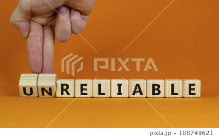 Unreliable or reliable symbol. Businessman turns wooden cubes and changes the word unreliable to reliable. Beautiful orange background, copy space. Business and unreliable or reliable concept. 108749621