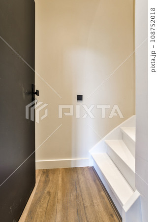 an empty room with wood flooring and white paint on the walls, there is a black door in the corner 108752018