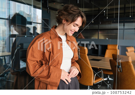 Portrait of confident young businesswoman, digital nomad posing in her office, wearing casual clothes and smiling 108753242