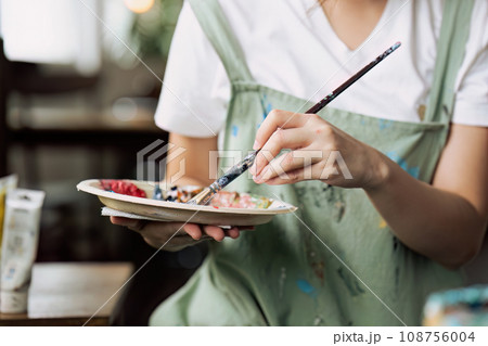 Female artist hold color palette and paintbrush for painting during hobby workshop 108756004