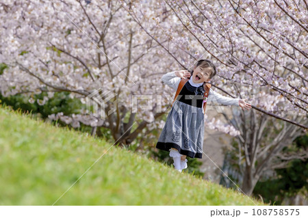 桜の咲く公園を歩くランドセル姿の一年生 108758575