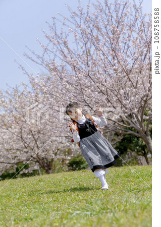 桜の咲く公園を歩くランドセル姿の一年生 108758588
