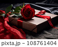 gift box with red ribbon and rose flower on black fabric 108761404