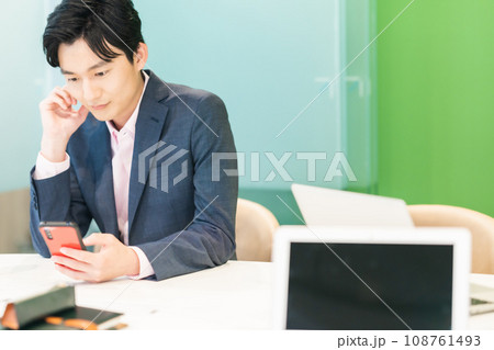 仕事中スマホで投資をするビジネスマン 108761493