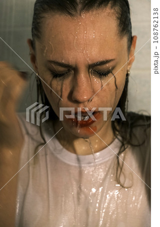 Portrait of a young girl with dripping makeup standing in the shower. Vertical Shot 108762138