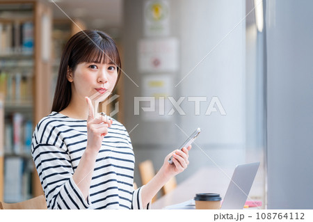 図書館でスマホを使っている学生。撮影協力：有明教育芸術短期大学 108764112