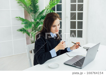 Beautiful woman in office working online on computer Beautiful woman in office working online on computer 108764154