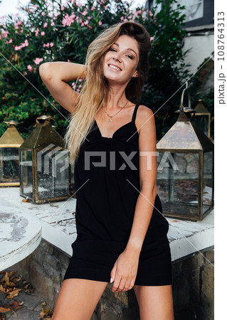 Beautiful slender woman in black summer dress Beautiful slender woman in black summer dress 108764313