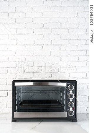 Mini electric oven against white brick wall in the kitchen 108764931