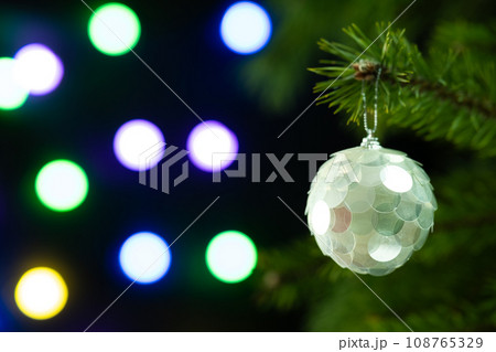 Christmas composition. Beautiful white ball on a Christmas tree closeup on a sparkling dark background Christmas composition. Beautiful white ball on a Christmas tree closeup on a sparkling dark background 108765329