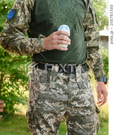 Dad, a Ukrainian military man, holds a baby bottle with milk for the baby. 108765380