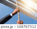 ビルから垂れ下がるロープを握るビジネスマン 108767312