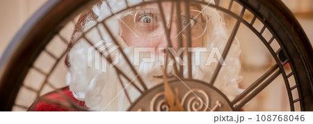 Five minutes to New year or Christmas midnight. Happy Santa Claus shows on the clock 108768046